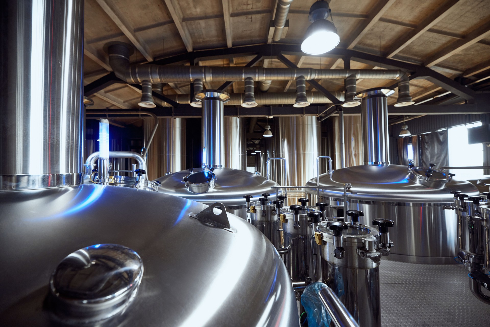 Filas de tanques de elaboración de cerveza industrial están listas, lo que refleja el equipo avanzado utilizado en la elaboración de cerveza de alta calidad.