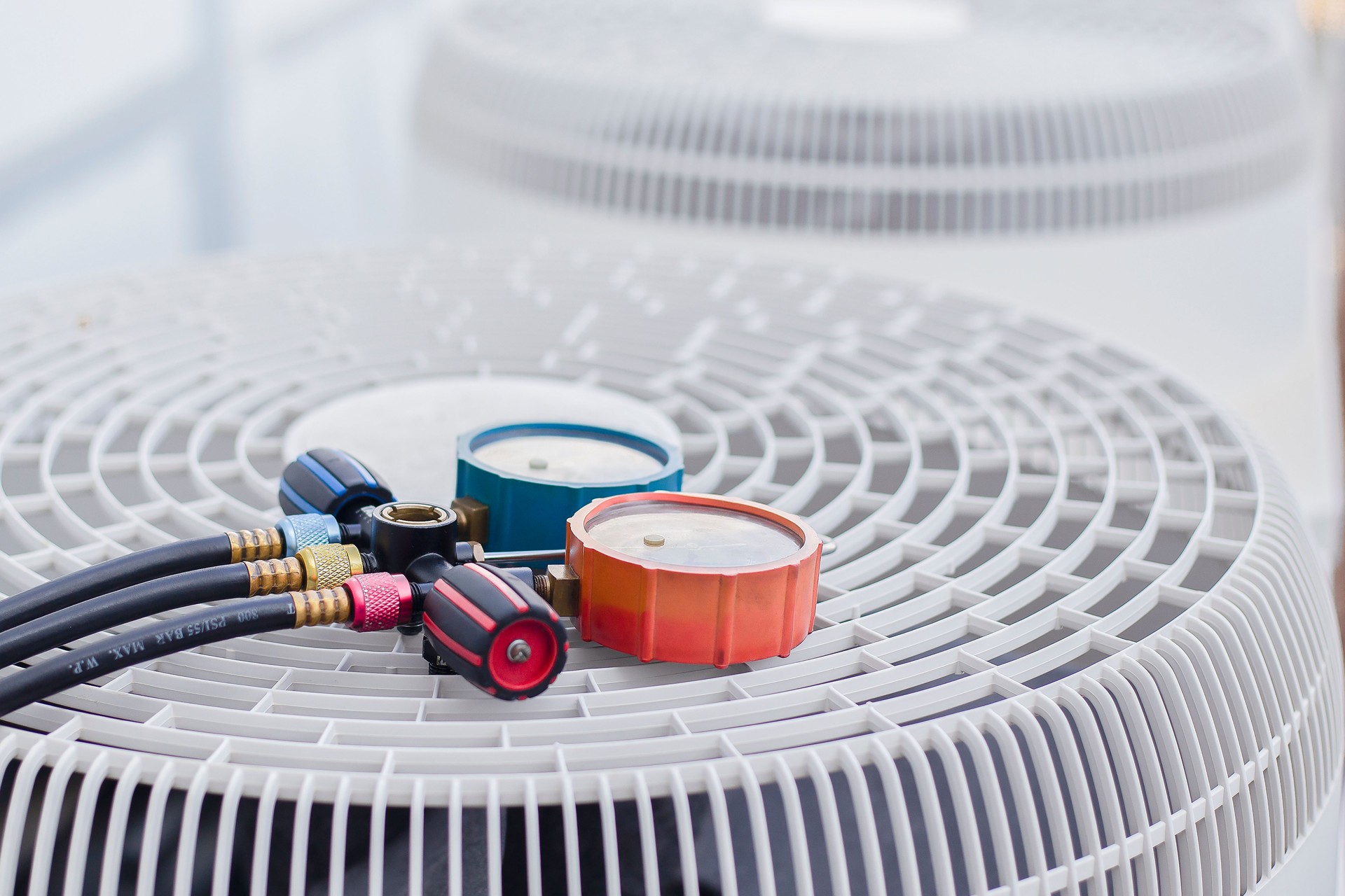 Air conditioning, HVAC service technician using gauges to check refrigerant and add refrigerant.
