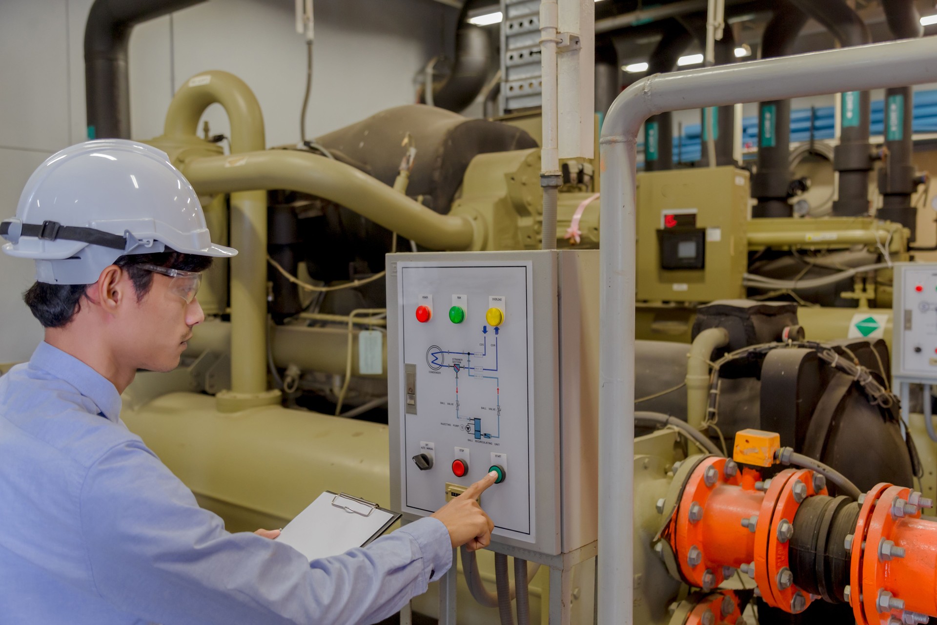 Engineer checking operating Industrial Chillers, hot water pump and pipe line for make high temperature condition in HVAC systems.