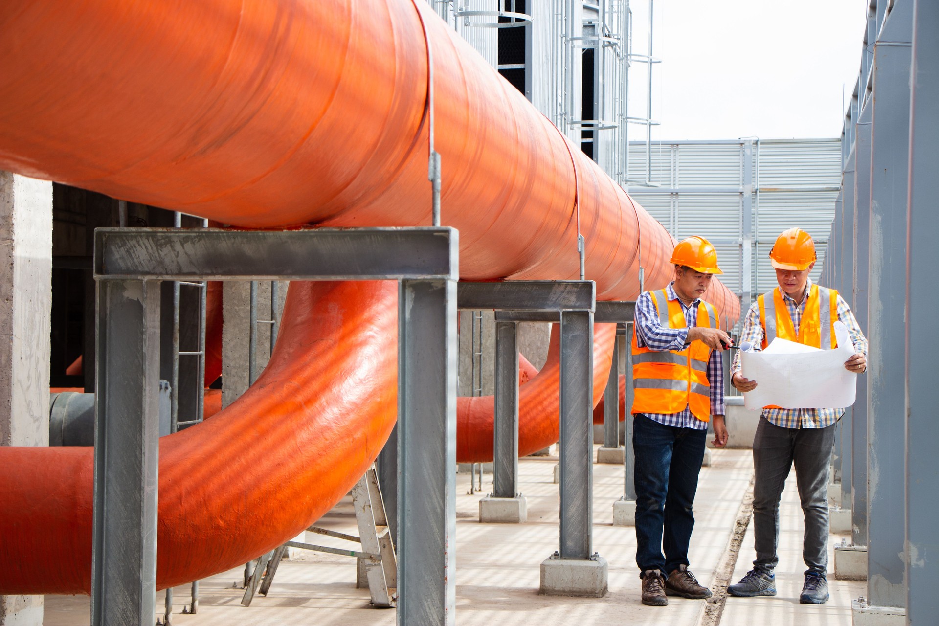 Ingeniero masculino asiático que inspecciona los accesorios de tubería y enfriadores, planta de refrigeración de la planta de refrigeración en la fábrica. Un mecánico masculino que lleva un casco y un chaleco de seguridad reflectante utiliza una comp
